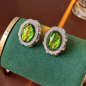 Macro shot of vintage emerald-cut opal earrings with sparkling zircon halo on velvet