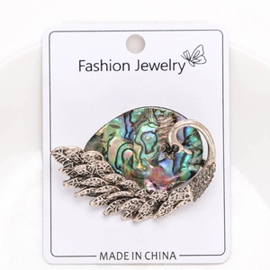 Macro detail of vintage peacock brooch featuring natural abalone shell inlay with floral texture