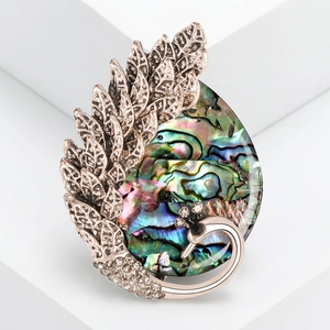 Vintage peacock brooch with colorful abalone shell and rhinestone inlay on white stand