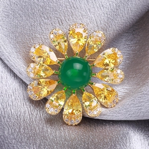 Macro shot of an elegant emerald green and yellow gemstone daisy brooch on silk