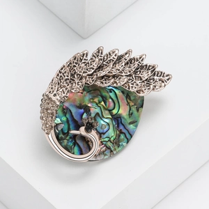 Retro peacock brooch featuring iridescent abalone shell and rhinestones on white steps