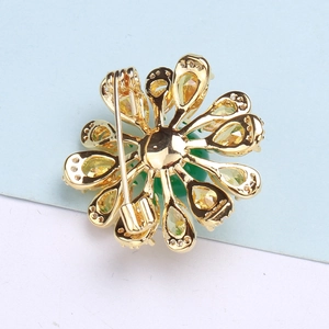 Detail view showing the golden metal back and safety pin clasp of the daisy brooch