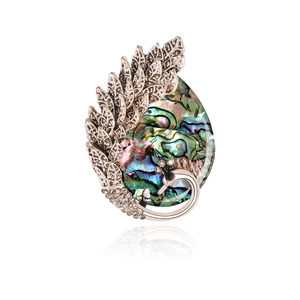 Detailed view of peacock feather brooch with iridescent abalone shell and crystal accents