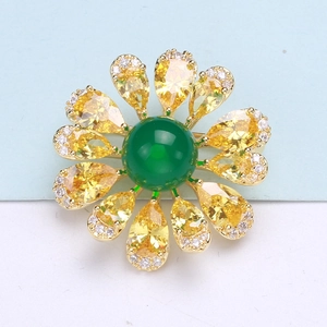 Macro shot of an elegant flower brooch with green center stone and yellow petals