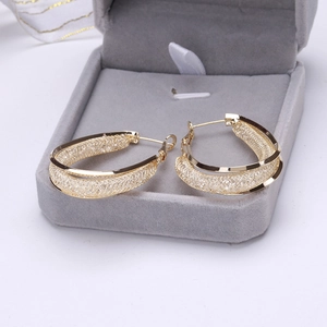 Boucles d'oreilles créoles dorées en maille avec détails brillants en écrin