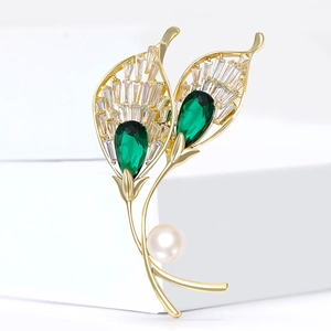 Elegant gold feather brooch with emerald green zircons and a white pearl accent