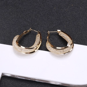 Boucles d'oreilles créoles dorées avec maille évidée et monture polie sur présentoir