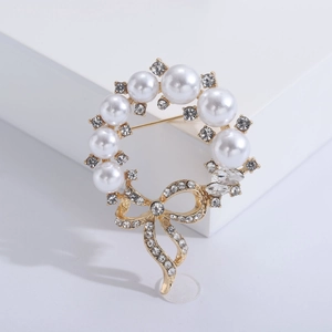 Elegante spilla a ghirlanda di perle con fiocco di strass su base geometrica bianca