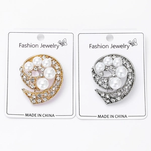 Detalle de broches de remolino en oro y plata con perlas y pedrería en tarjeta
