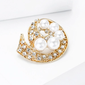 Detalle de broche dorado con forma de S decorado con perlas blancas y brillantes strass