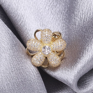 Détail d'une broche fleur rotative sertie de cristaux sur fond de soie plissée