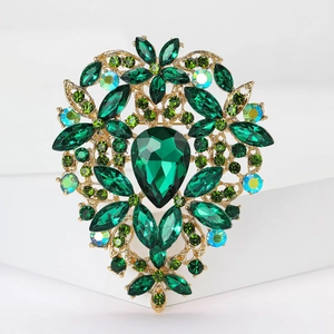 Macro shot of vintage gold flower brooch with green crystals and rhinestone details