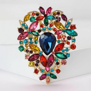 Detailed macro of a vintage gold alloy brooch with a blue teardrop stone and colorful rhinestones