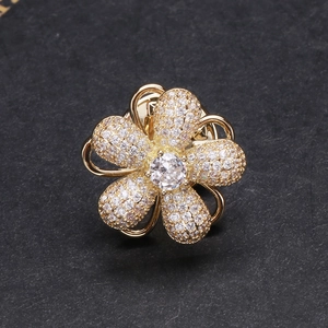 Broche fleurie exquise en or avec pétales en zircone blanche sur fond texturé noir
