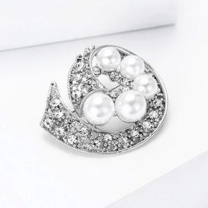 Vista detallada del broche plateado con perlas blancas y diamantes de imitación