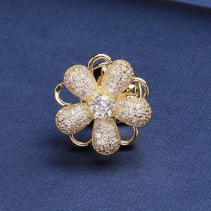 Vue macro de la broche fleur rotative dorée avec zircons blancs sur tissu bleu foncé