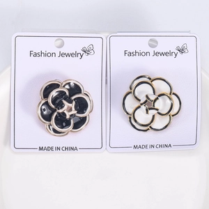 Detailed close-up of enamel camellia brooches in black and white with gold edges