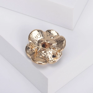 Golden camellia flower brooch with pin clasp on white geometric stairs, back view details