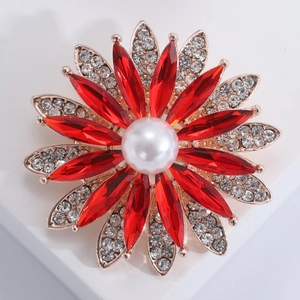 Détail d'une broche tournesol avec strass rouges et une perle blanche au centre
