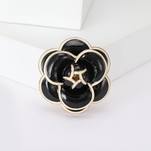 Elegant black enamel camellia flower brooch with gold plating on a white display stand