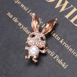Détail d'une broche lapin en finition or rose avec cristaux colorés et une perle blanche