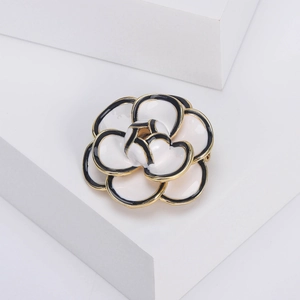 Elegant black and white enamel camellia brooch with gold trim on geometric stands