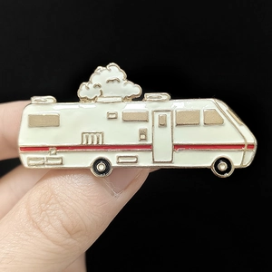 Détail d'un pin's émaillé en forme de camping-car avec des accents dorés élégants