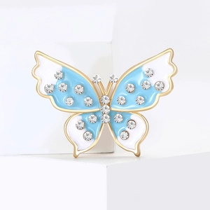 Broche papillon dorée élégante avec émail bleu et strass sur support blanc géométrique