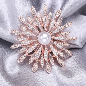 Close-up of luxury sun flower brooch featuring detailed rhinestones and a central pearl