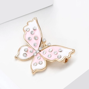 Détail de la broche papillon avec ailes en émail rose et strass scintillants sur métal doré