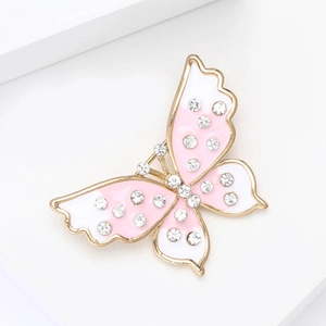Détail d'une broche papillon dorée avec émail rose et strass brillants pour femme