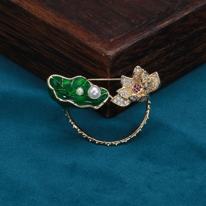 Détail d'une broche lotus avec émail vert, perles et cristaux sur finition dorée
