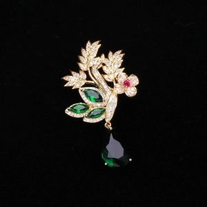 Détail d'une broche fleurie en cristal avec pendentif goutte émeraude sur velours