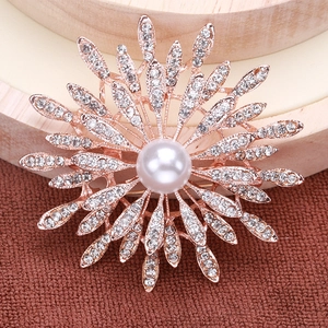 Macro shot of rose gold sunflower brooch with small crystals and center white pearl