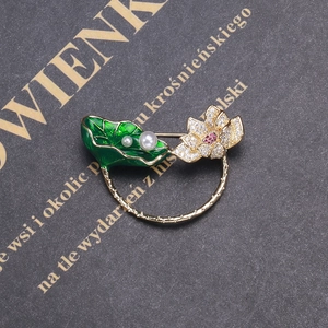 Détail macro d'une broche nénuphar en émail et fleur de zircon sur livre ancien