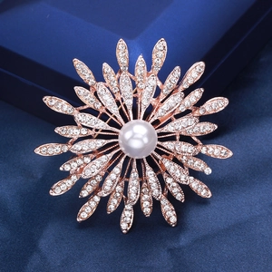 Macro shot of luxury sunburst brooch with pavé crystals and a large pearl center