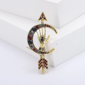 Vintage gold brooch with moon arrow and eye design inlaid with red and black rhinestones