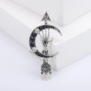Vintage arrow moon brooch with palm eye design and blue crystals on white background