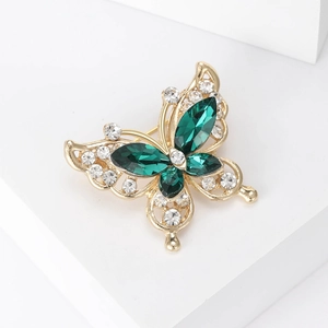 Close-up of golden butterfly brooch with emerald crystals and white rhinestones