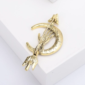 Retro gold moon arrow brooch with hand motif displayed on a white geometric block