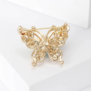 Detailed back view of golden butterfly brooch showing safety pin and hollow carvings