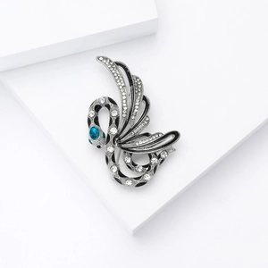 Macro detail of a silver swan brooch featuring black enamel and crystal rhinestones