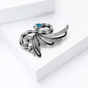 Detailed close-up of a silver snake brooch with sparkling rhinestones and blue gem head