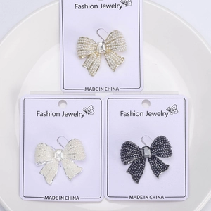 Detailed macro view of elegant bow brooches in gold, silver, and black with pearls