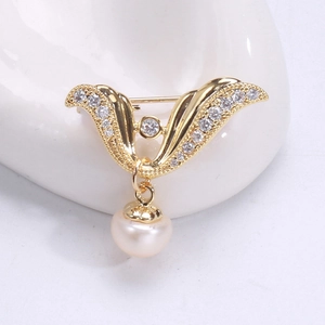 Macro view of gold angel wing brooch with sparkling zircons and a hanging pearl