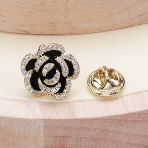 Elegant gold camellia brooch with black enamel petals and micro-set cubic zirconia accents