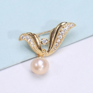 Detail of gold angel wing brooch with white cubic zirconia and a pink pearl drop