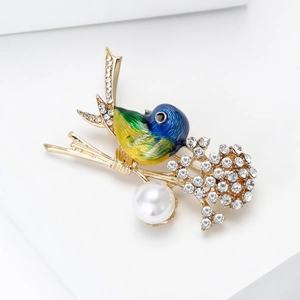 Close-up of bird brooch with enamel gradient, sparkling rhinestones and a white pearl