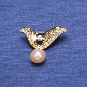 Detail of angel wing pearl brooch with sparkling cubic zirconia on blue background