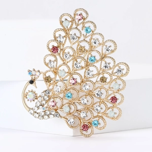 Elegant gold peacock brooch with colorful rhinestones on a minimalist white stage